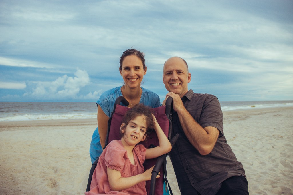 Man and woman with a handicapped child on a beach.